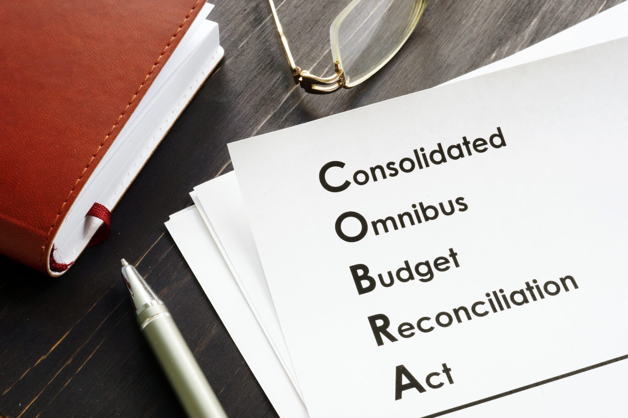 COBRA (Consolidated Omnibus Budget Reconciliation Act) written on white piece of paper on a desk.